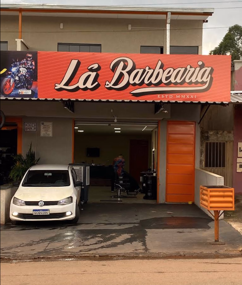 Fachada da Lá Barbearia com letreiro laranja e porta laranja