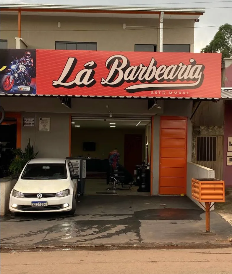 Fachada da Lá Barbearia, com letreiro e porta laranja